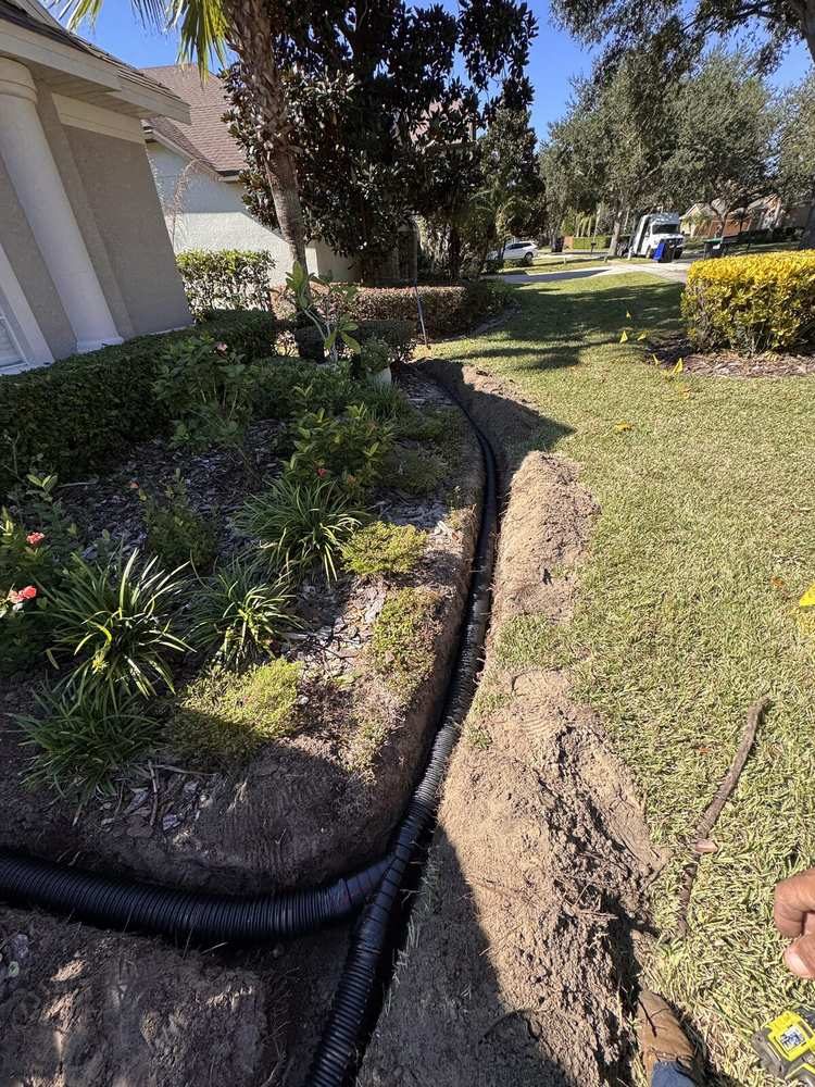 Solid drain pipe routed through trench along landscaped bed in Central Florida